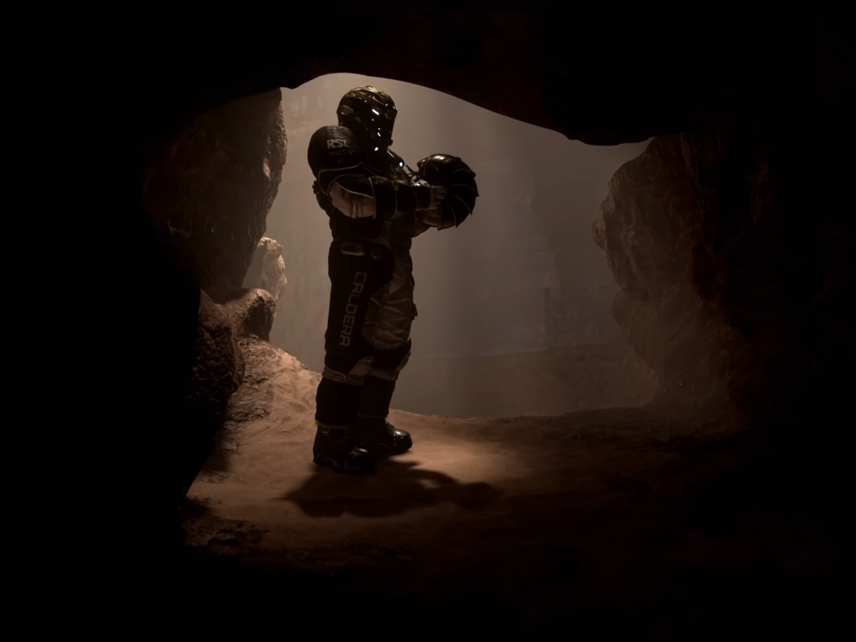 Suited Star Citizen character holding a helmet inside a cave